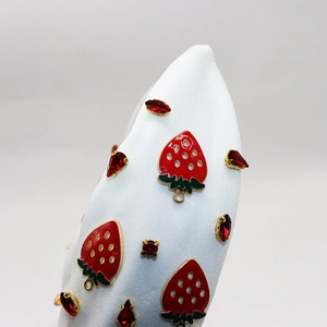 Detail view of white fabric headband featuring strawberry charms and red rhinestones