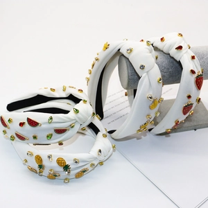Detail of white knotted headbands with rhinestones and colorful fruit metal charms