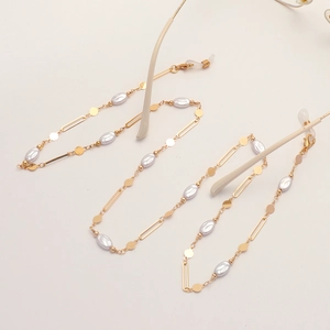 Golden eyeglass chain with irregular pearls and oval metal discs on a flat lay background