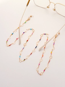 Rainbow beaded eyewear chain with gold star and moon charms on soft beige background