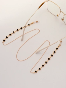 Detail of gold chain glasses strap featuring black heart charms and silicone loops