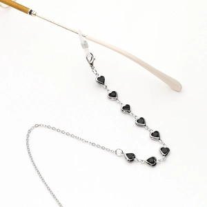 Detailed close-up of a silver-toned eyewear chain featuring black heart-shaped glass beads