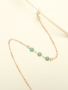 Detail of golden metal eyewear chain with blue enamel daisy charms and secure lobster clasp