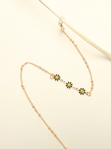 Detail of golden eyeglass chain featuring black daisy charms and silicone loop connectors