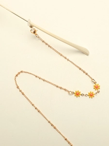 Close-up of gold glasses chain with daisy charms and silicone loop on eyeglass temple