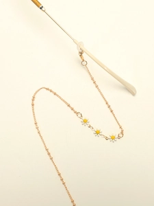 Detail of golden glasses chain with white daisy pendants and silicone anti-slip loops