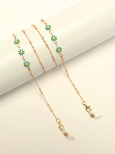 Golden eyewear chain with blue daisy charms on a minimalist display stand