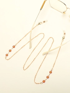 Close-up of golden eyewear chain with red and yellow daisy enamel flower charms