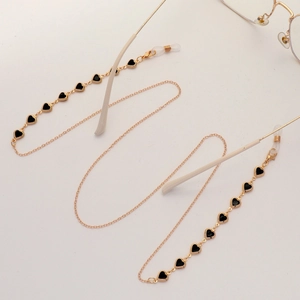 Golden eyewear chain with black heart charms and silicone loops on white background