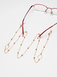 Golden eyewear chain with geometric diamond charms and small beads on red glasses