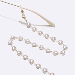Golden eyewear chain with heart-shaped pearls and silicone loops shown at a 45-degree angle
