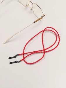 Detailed macro view of red braided eyewear strap with adjustable rubber ends and metal slider