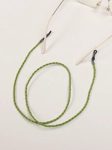 Detail of green braided eyewear strap with adjustable rubber ends on glasses