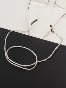 Detail view of cream braided glasses chain with silver slides on black and white background