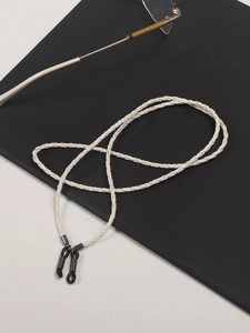 Detail of white braided leather eyewear cord with black metal buckle and rubber loops
