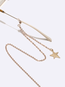 Golden metal glasses chain with star pendant and anti-slip rings on cream temples