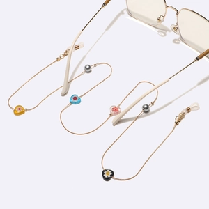 Chaîne à lunettes dorée avec cœurs en verre colorés et perles grises sur lunettes