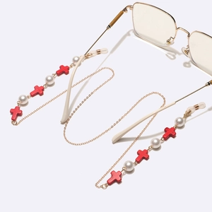 Chaîne de lunettes dorée avec perles blanches et croix rouges sur fond blanc