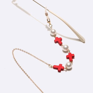 Chaîne de lunettes dorée avec croix rouges et perles sur branches blanches