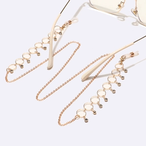 Golden eyewear chain with round hollow circles and clear sparkling crystals on white background