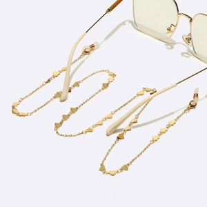 Golden metal eyewear chain with heart pendants and non-slip silicone loops on white background