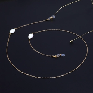 Minimalist gold eyeglass chain featuring white teardrop shell charms on a black background