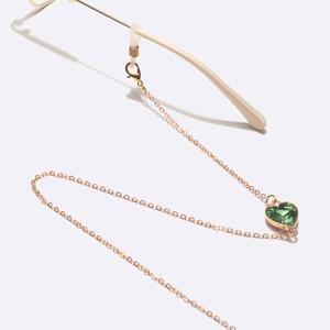 Détail de la chaîne de lunettes dorée avec cristal cœur vert et attaches silicone