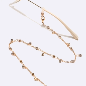 Golden eyeglass chain with transparent rhinestones and polished beads on white background
