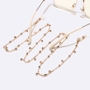 Elegant gold metal glasses chain with crystal rhinestones and beads on white background