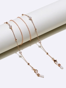 Chaîne à lunettes dorée élégante avec perles blanches et perles dorées sur support blanc