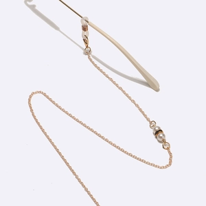 Chaîne de lunettes dorée avec strass noirs et perles sur fond blanc neutre