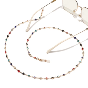 Chaîne de lunettes dorée avec strass colorés et boucles en silicone sur fond blanc