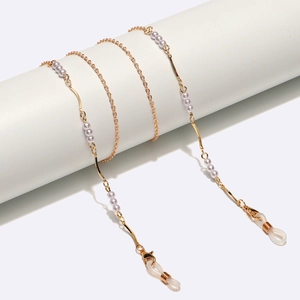 Elegante goldene Brillenette mit weißen Perlen und Metallstäben auf weißem Display