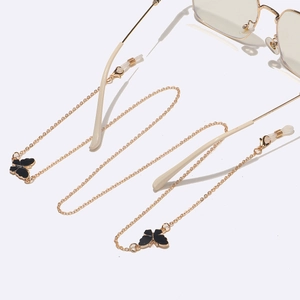 Chaîne de lunettes dorée style punk avec pendentifs papillon noirs sur fond blanc
