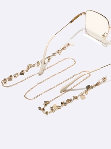 Golden eyewear chain with heart pendants and rhinestones on beige glasses frame