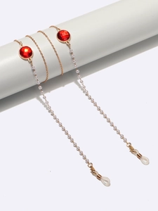 Detail der eleganten goldenen Brillenkette mit roten Kristallen, Perlen und Silikonschlaufen