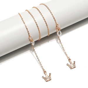 Golden eyewear chain with crown pendant and rhinestones on a white podium