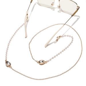 Detail of golden glasses chain with white pearls and water-drop crystal charms