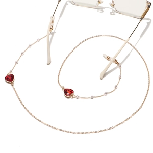 Détail de la chaîne de lunettes dorée avec cristaux de cœur rouges et petites perles