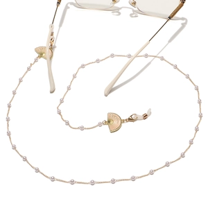 Chaîne à lunettes dorée avec perles blanches et pendentifs éventails roses sur fond blanc