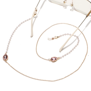 Detail of gold glasses chain featuring white pearls and pink teardrop crystals with loops