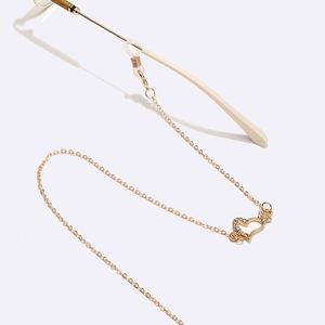 Golden eyewear chain with heart pendant and rhinestones on a white background