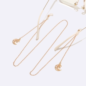 Golden eyewear chain with star moon charms and pearls on white reflective background