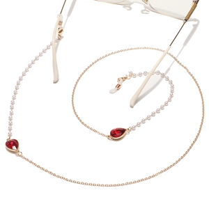 Detail of gold glasses chain with white pearls and red water drop crystals