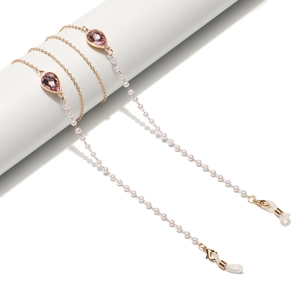 Elegant gold glasses chain with pink teardrop crystals and white pearls on white background