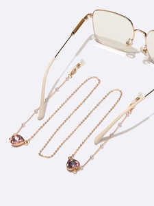 Détail de la chaîne de lunettes dorée avec perles et cristaux roses en forme de cœur