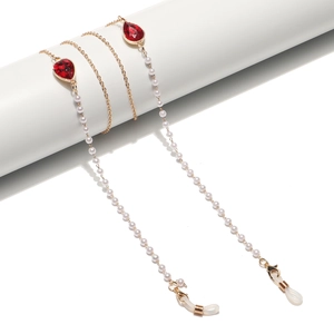 Gold glasses chain with red teardrop crystals and white pearls on a white stand