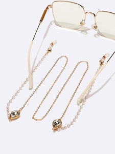 Golden eyewear chain with white pearls and teardrop crystal pendant on white surface