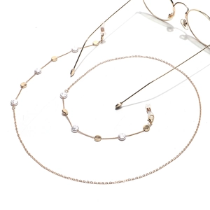 Gold glasses chain with round pearls and metal discs on a white background