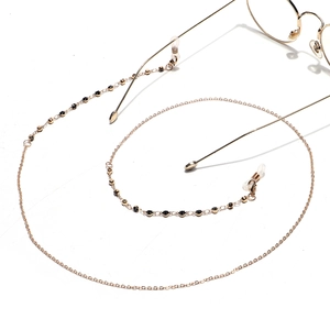 Fashionable gold eyewear chain with black rhinestone beads and silicone loops on white background